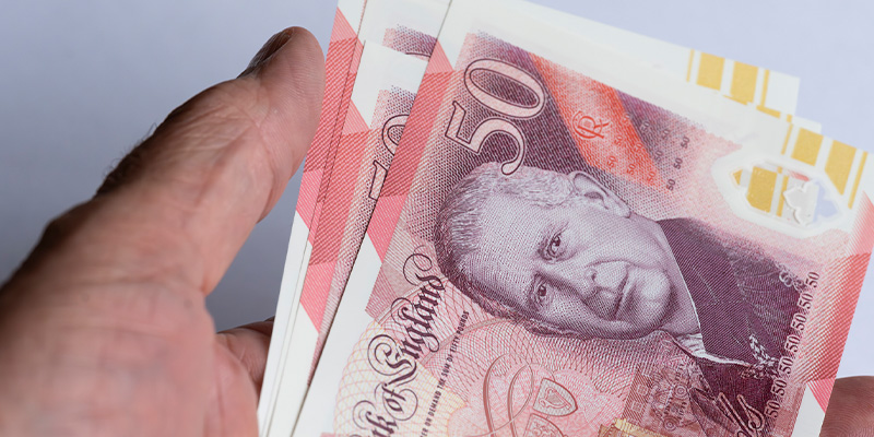 New Designs for British Banknotes holding bank notes - New Designs for British Banknotes